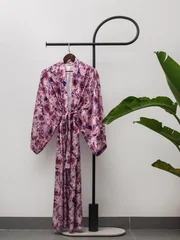 Luxury  kimono robe hanging on minimalist clothing rack with tropical plant © blackday