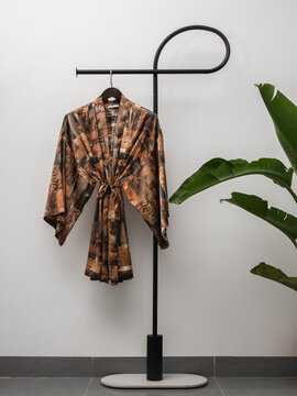 Luxury  kimono robe hanging on minimalist clothing rack with tropical plant
