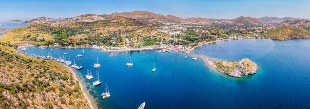 Aerial view capturing the scenic Gumusluk bay in Bodrum, Turkey, showcasing yachts moored in the clear Aegean Sea
