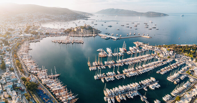 Bodrum, Turkiye marina packed with numerous yachts and sailing vessels, featuring castle and coastal city along the Aegean Sea