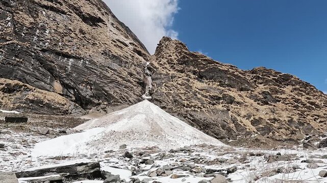Avalanche snow cone beneath a towering cliff and frozen cascade, Annapurna Sanctuary, Nepal