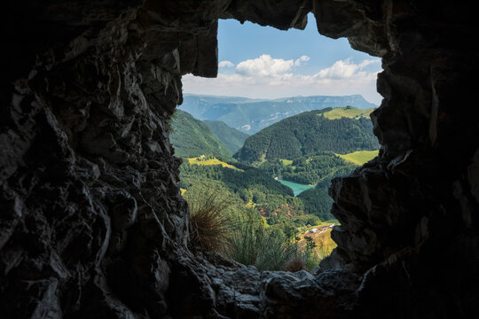 Nature exploration and travel landscape viewed through a rocky cave along the road, wiht in the background the Pr&agrave; da Stua lake Monte Baldo Natural Park, Brentonico, Trentino, Veneto, Italy.