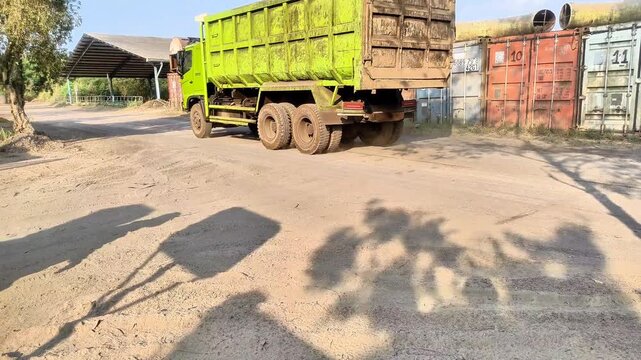 Industrial dump truck driving on a dusty rural road