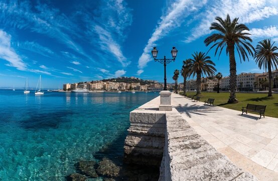 Scenic coastal in saranda promenade with turquoise water palm trees benches stone walkway sailboats hillside town and bright sky with streaked clouds for travel stock generated ai
