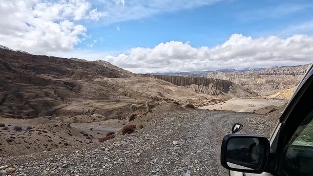 Dusty 4WD road winding past eroded cliffs near Yara Gaun, Upper Mustang, Nepal