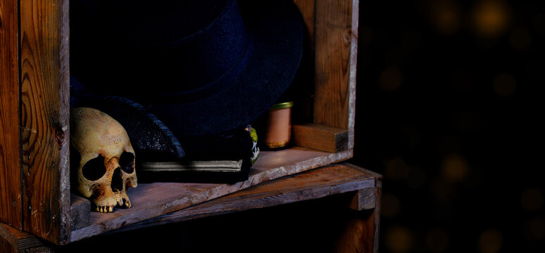 Spooky Halloween shelf with skull and witch hat, dark aesthetic and copy space of vintage aesthetic with background bokeh lights