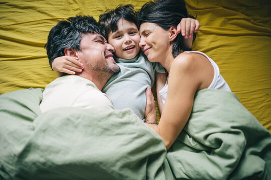 Happy family with son hugging in bed at home in the morning