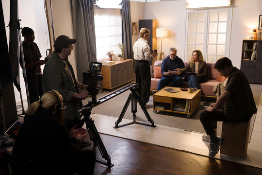 A film crew prepares a scene with a man and a woman in a studio