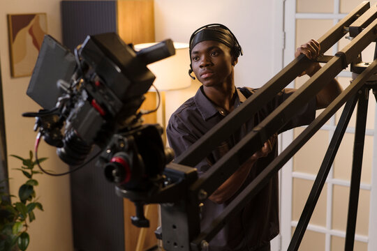 Cameraman operates a camera crane during an indoor film production