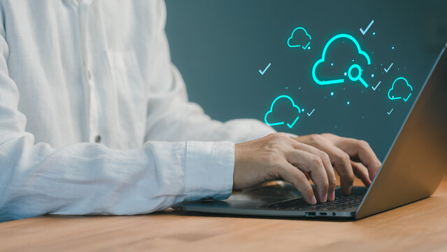 Man typing on a laptop computer with glowing cloud computing icons. Digital data storage, network, and internet technology concept.