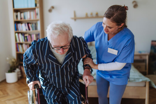 Smiling home caregiver assisting senior man at home