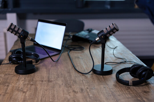 Microphones with headset and laptop on desk in recording studio