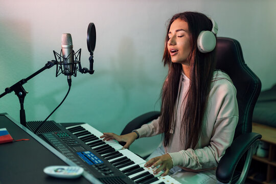 Young female singer singing while playing piano in studio