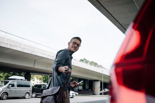 Young businessman using remote control key of car