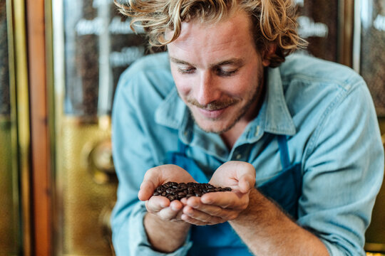 Coffee roaster in his shop smelling at coffee beans