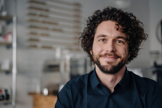 Proud coffee shop owner standing behind counter