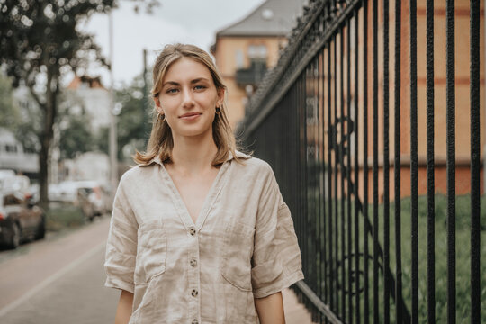 Young woman with blond hair standing on footpath