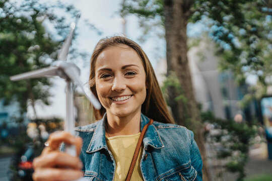 Smiling young woman holding wind turbine model