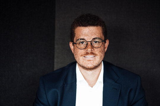 Smiling businessman with freckles looks at camera in the office