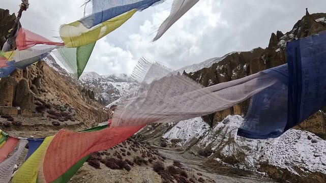 Tibetan prayer flags fluttering above snowy valley at Luri Gompa, Upper Mustang, Nepal