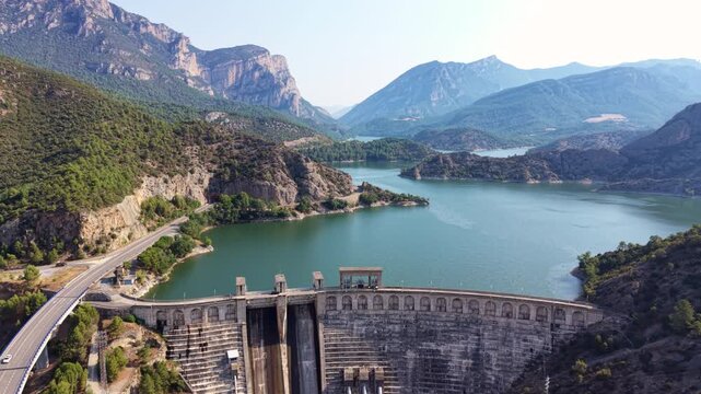 Aerial view of Oliana dam and reservoir winding through rugged mountainous terrain, Segre River valley, Lleida, Catalonia, Spain. Turquoise water surrounded by forested rocky peaks