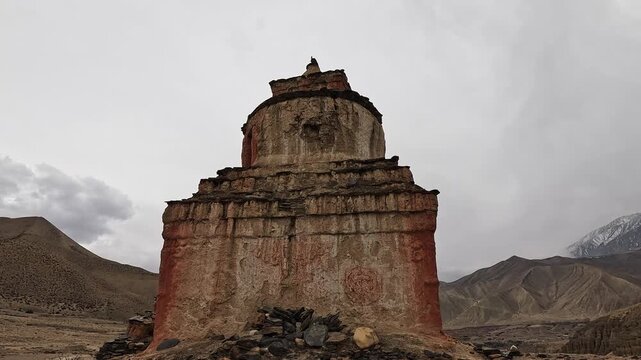 Ancient weathered chorten with red ochre base below barren hills, Dhakmar, Upper Mustang, Nepal