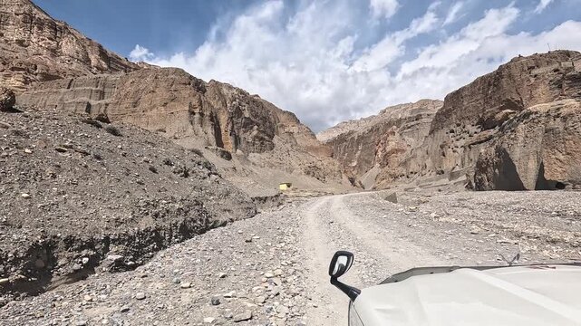 Driving POV along a rough gravel road through a barren scree gorge toward Chele, Upper Mustang, Nepal