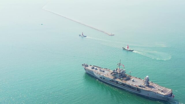Amphibious Assault Ship. Navy aircraft carrier navigates vibrant turquoise ocean under brilliant sky. This powerful ship showcases strength and capability in expansive maritime environment,