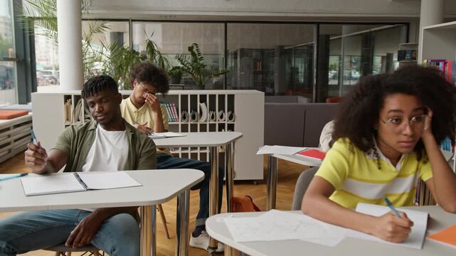 Four diversity students classmates listening boring course lesson lecture at tables group of multiethnic people studying learning burnout sleepy in university high school college boredom study learn