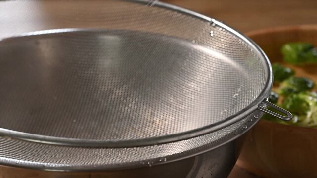 Woman hand washing fresh broccoli with clean water in a wooden bowl and pick up into a sieve, meal prep