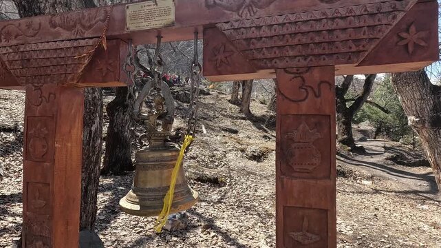 Shiva brass temple bells hanging under carved wooden gate, Muktinath, Nepal