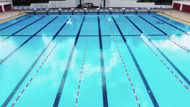 The High angle view of an empty outdoor of olympic size swimming pool with blue water and black lane lines background