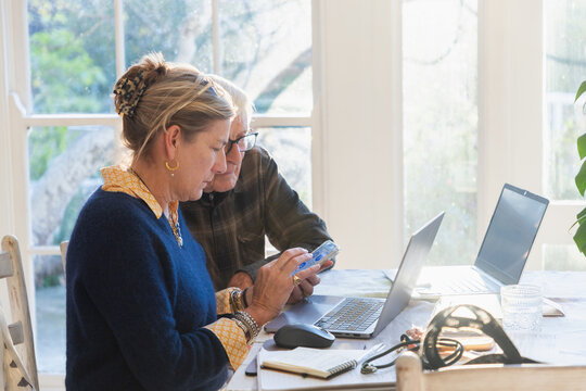 adult daughter helping her elderly father with his finances using laptop