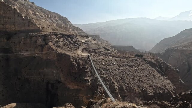 Eroded canyon dirt switchback road footbridge gorge Upper Mustang Nepal landscape
