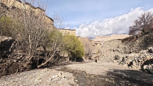 Old mud-brick houses of Tetang village on an eroded bluff above a dry riverbed, Upper Mustang, Nepal 