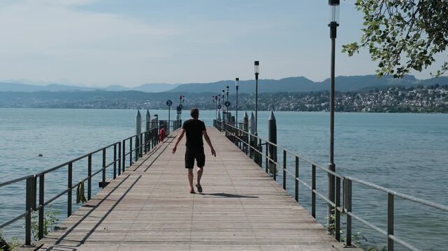 Schiffsanlegesteg Z&uuml;richhorn am Z&uuml;richsee in der Schweiz, Mann spaziert auf Steg am See in Z&uuml;rich im Hochsommer