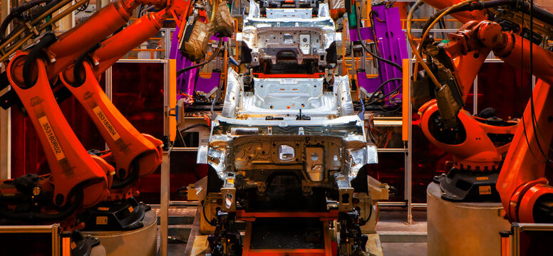 Robotic arms in an automobile manufacturing plant are performing automated tasks.