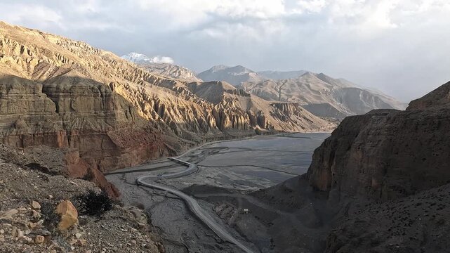 Wide panoramic view Kali Gandaki valley from Chele at sunset, winding road, eroded cliffs Nepal