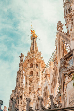 Ornate gothic architecture of Milan Cathedral spires against a bright sky.