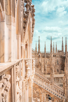 Architectural view along the cascading white marble roof terraces of the Duomo di Milano, showcasing the complex gothic structure, pinnacles, and intricate flying buttresses.
