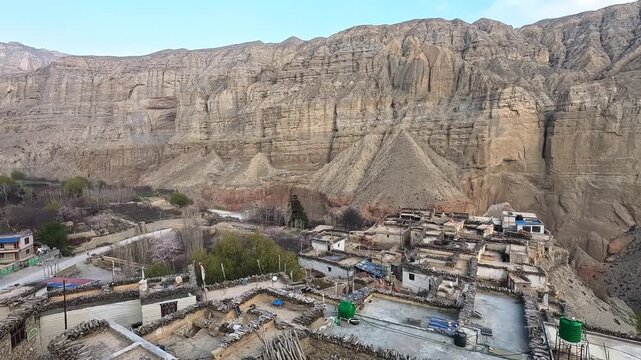 Chele village rooftop overview, spring cherry blossom, dramatic sandstone cliffs, Upper Mustang Nepal