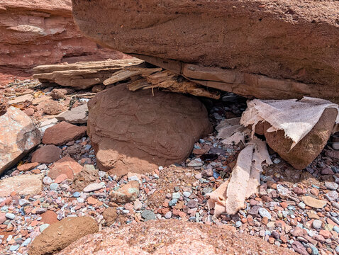 Gaspesie, Quebec, 07 June 2026 : Weathered red rock formations and colorful pebbles cover a natural, rugged landscape with debris