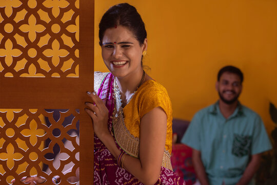 Portrait of smiling Gujrati woman standing and her husband sitting behind