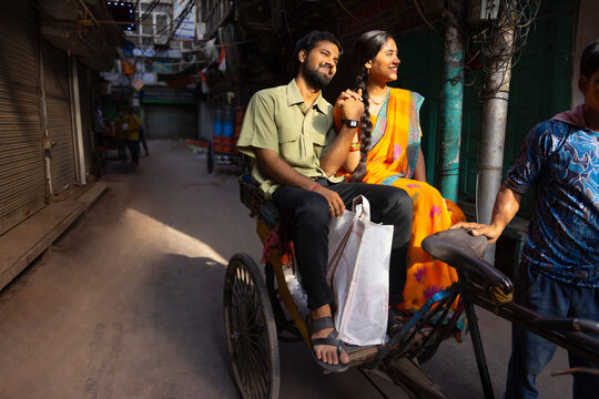 Happy young couple riding rickshaw with holding their hands together