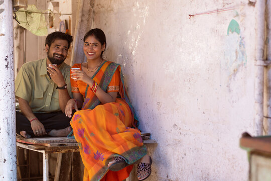 Happy couple sitting on table and drinking tea in front yard