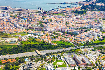 Obraz premium Panoramic aerial view of Lisbon Almada district showcasing urban infrastructure highway toll gate green parks and harbor with ships Portugal