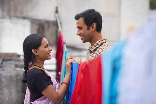 Couple hanging out wet clothes on washing line in the backyard
