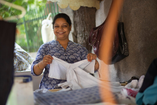 A woman Dhobi ironing clothes with an old coal heated iron
