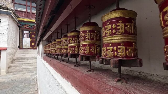 Close-up dolly in prayer wheels red-gold decorated, Buddhist shrine Samten Choling Gompa