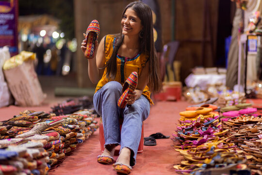 Gril selecting from two pairs of sandals in street shop
